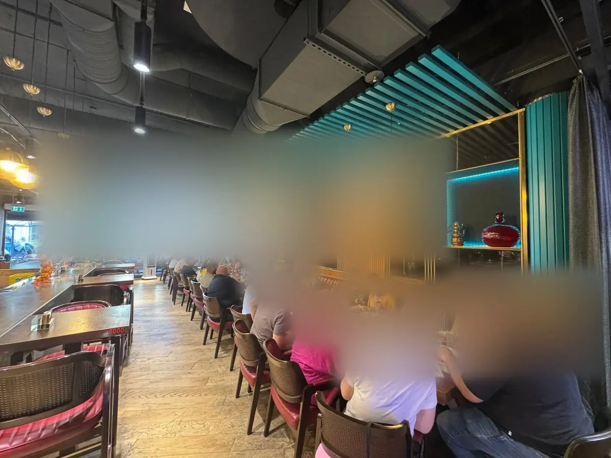 Blick durch den ZIYAFET Grill auf die lange Tafel der Community.